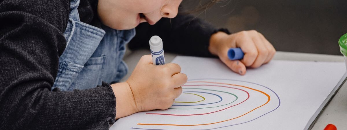 Child making a rainbow with markers