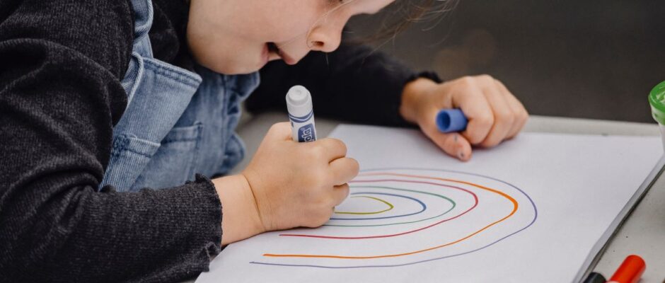Child making a rainbow with markers