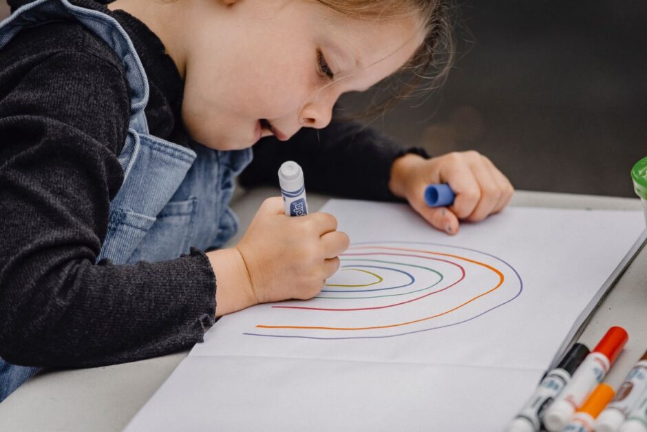 Child making a rainbow with markers